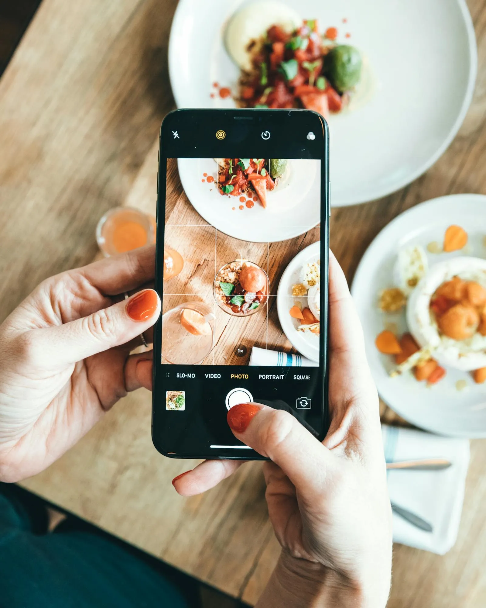 A person uses a smartphone to photograph a plated meal from above — the core interaction behind AI calorie counters