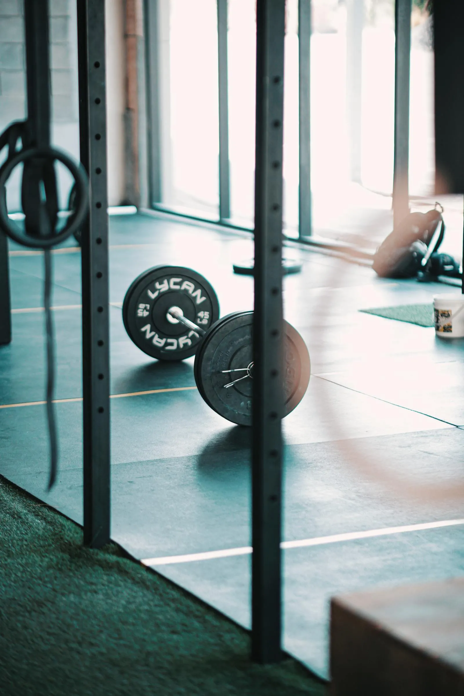 A loaded barbell rests on a gym floor in natural light, ready for the next session